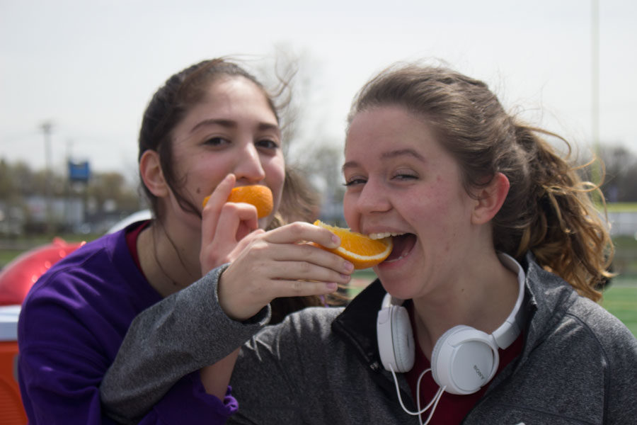 Senior Anna Locklear and Serena Chapa share orange slices after finishing the 5k.