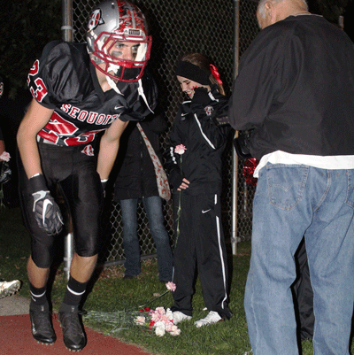 Samantha Kempf smiles as Junior Andrew Hare and the rest of the Antioch varsity football team placed assorted carnations at her feet on Friday night before the Sequoits’ conference championship game against Grayslake North High School as a gesture to her for fighting a tumor located in her brain.
