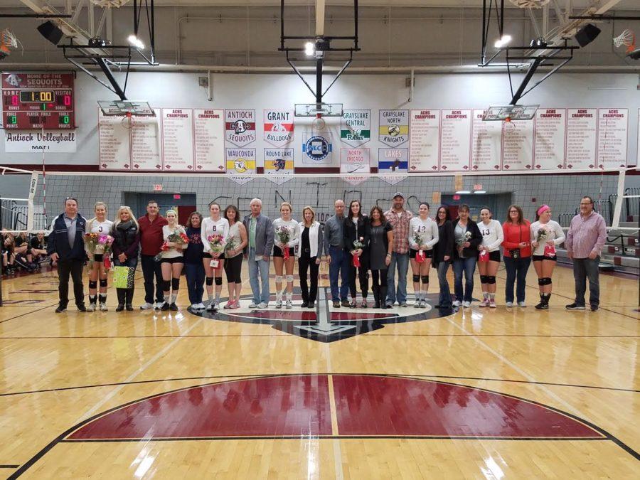 The seniors on the girls volleyball team smile for a picture before their senior night game.