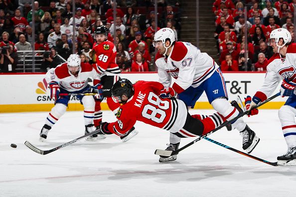 Patrick Kane shoots the puck while getting hit by Max Pacioretty