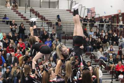 Cheer flipping their way to victory in cheerleading showing off their bows.