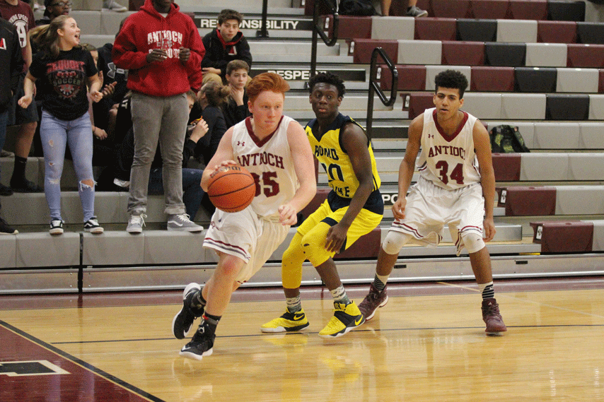 During a basketball game against Round Lake High School, junior Alex Larson dribbles to go take a shot. 