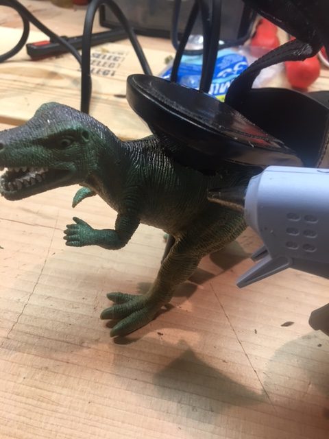 Place hot glue around the hole in the dinosaurs, securing it to the shoe on the top and the bottom of the dinosaur.