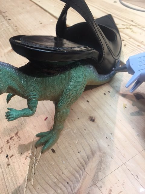 Attach the dinosaur tail to the base of the shoe, securing with hot glue.