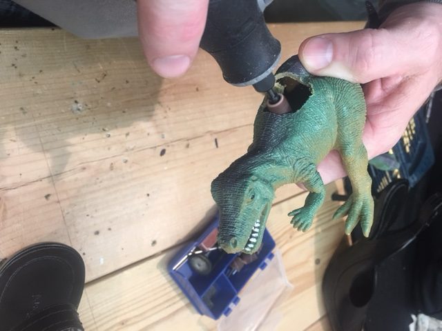 Widen the hole with the Dremel tool in the back of the dinosaur so that the wider area of the heel can rest comfortably. 