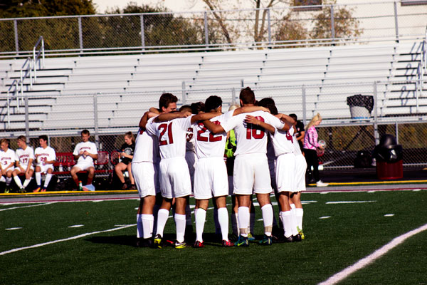 The soccer team huddles up before the start of their game.