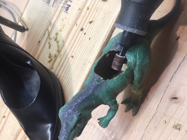 Widen the hole with the dremel tool in the back of the dinosaur so that the wider area of the heel can rest comfortably.