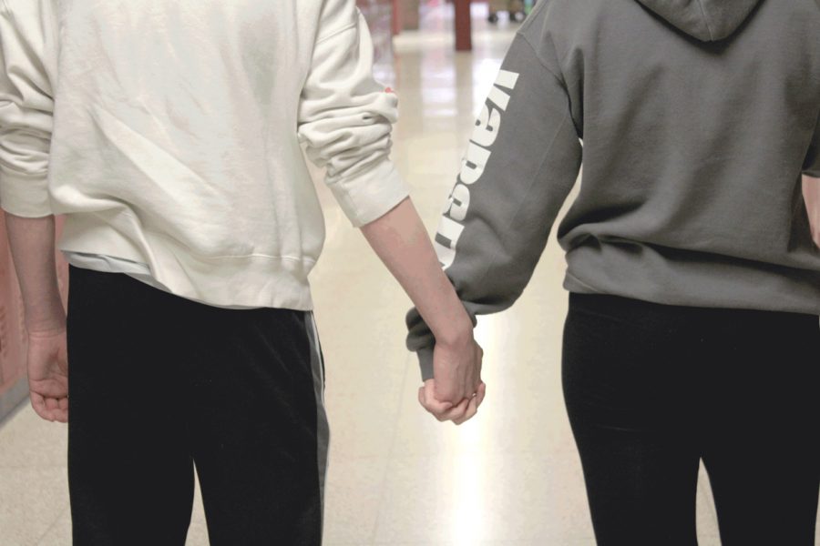 An ACHS couple holds hands in the hallway
