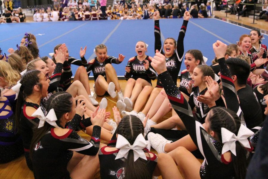 The varsity cheer team raises their hands in the air in triumph as their name was announced as one of the five teams to qualify for state