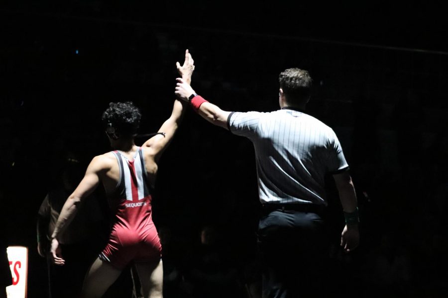 Elijah Reyes wins his match against the Grant Bulldogs and raises his hand in victory.