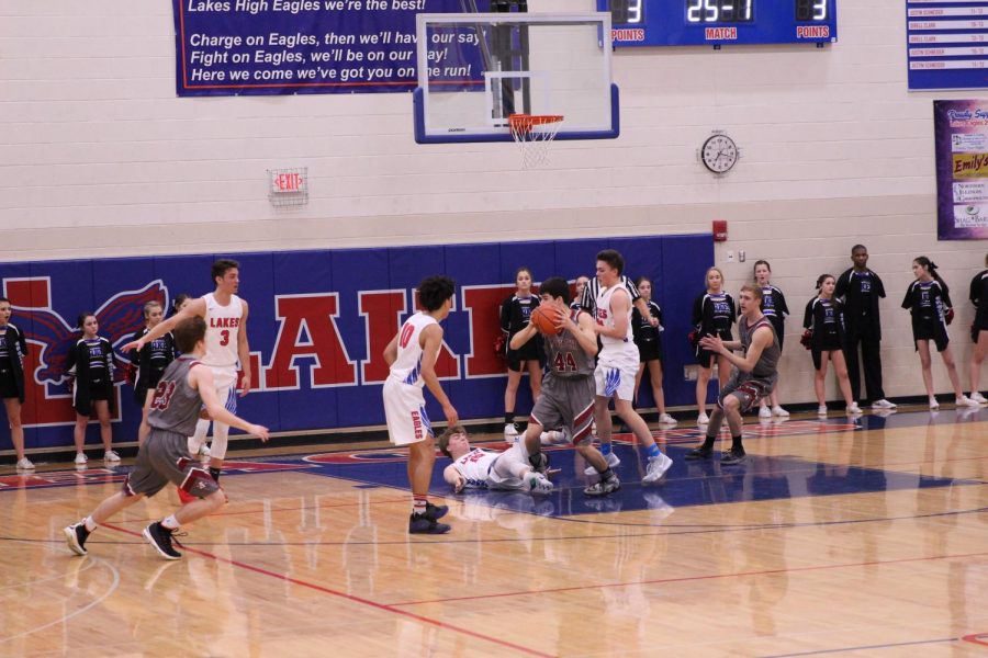 Senior Elias Vanderwagen looks to pass the ball as the Lakes defender takes a tumble.