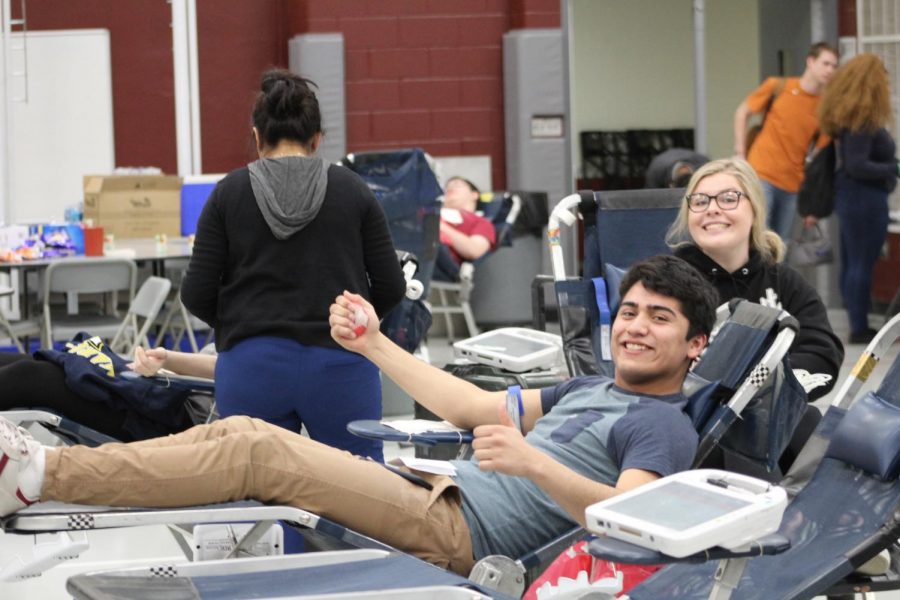 Seniors Christian Ortiz and Victoria Henkel smile as they donate blood.