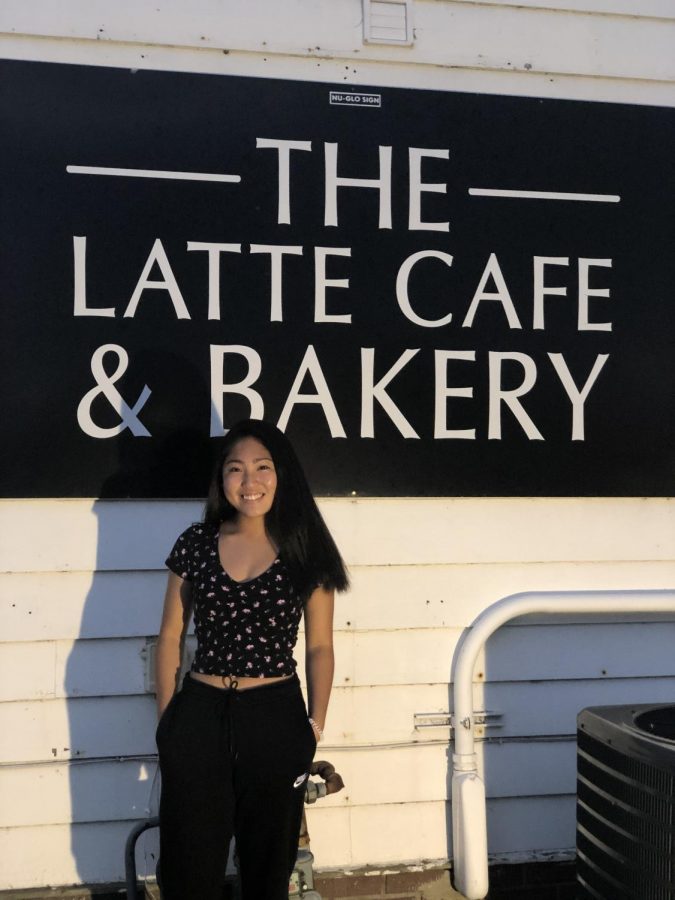 Coffee lover and enthusiast Olivia Lahti stands by the iconic Latte Cafe and Bakery sign in Antioch, Ill.