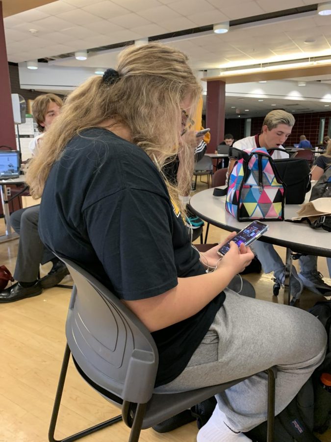 A student at lunch listens to Billie Eilish with her earbuds.