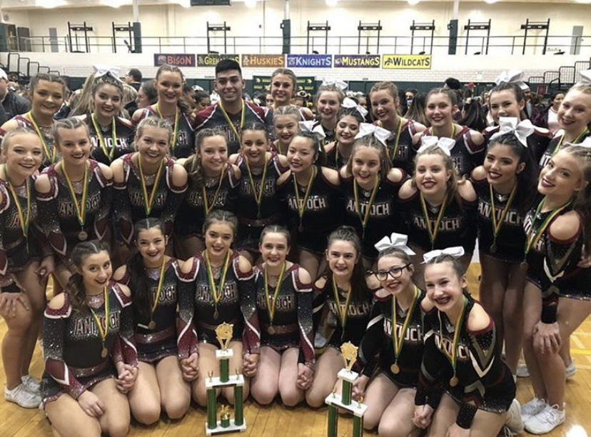Junior varsity and varsity take a group picture with their first place trophies that they won at the Fremd cheer competition.