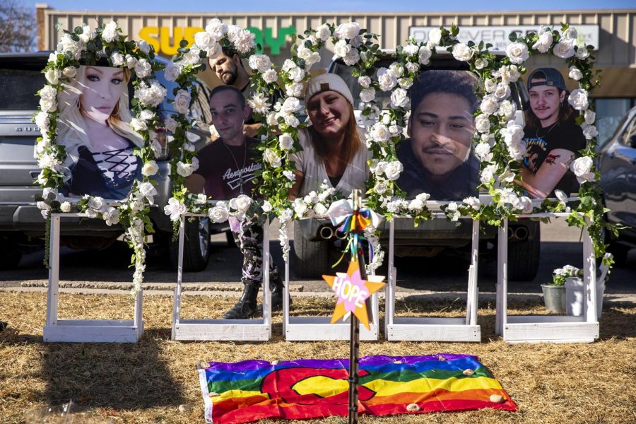 Photos of Kelly Loving (left to right), Derrick Rump, Ashley Paugh, Raymond Green Vance and Daniel Aston stand above a memorial outside of Colorado Springs Club Q. Nov. 22, 2022.